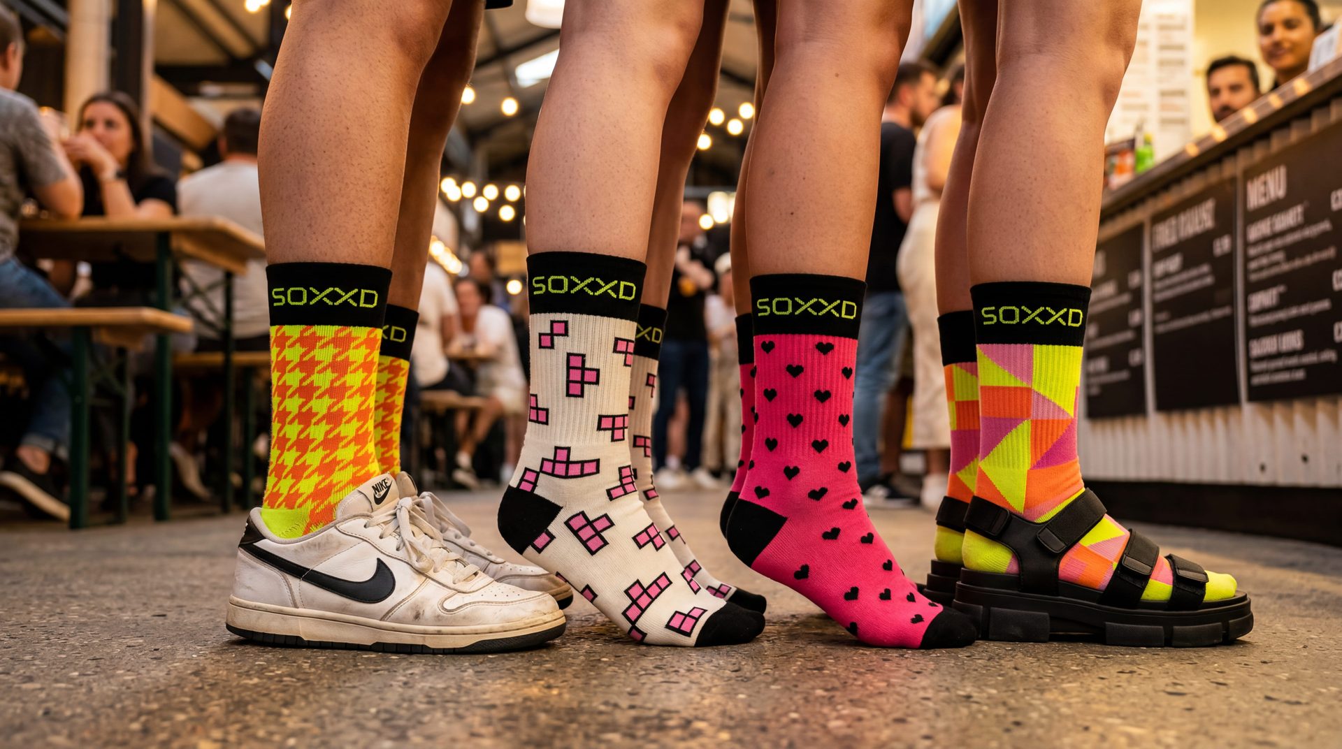 Four pairs of legs side-by-side wearing different SOXXD patterns at a Berlin food market.